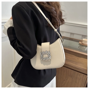 Détail d'un sac demi-lune crème avec boucle luxueuse en cristal et fine bandoulière