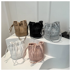 Detail view of five pleated drawstring bucket bags in beige, black, silver, white and pink