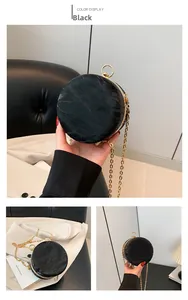 Detail of black round evening bag with pleated texture and gold chain strap