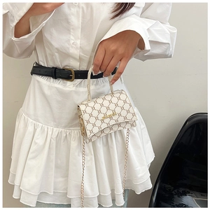 Detail of white mini flap bag featuring vintage brown monogram and gold chain strap