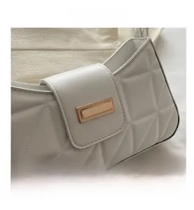 Detalle de patrón acolchado blanco y hebilla de metal dorado en un bolso de hombro grande