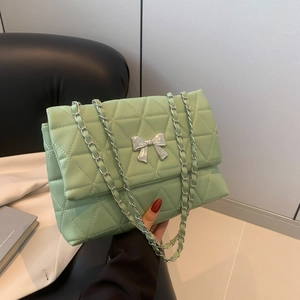 Sac bandoulière vert menthe matelassé avec nœud argenté présenté avec élégance à la main