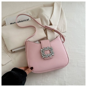 Gros plan d'un sac à bandoulière rose avec une grande boucle en strass étincelants