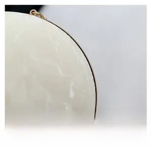 Detail of round marble bag showing white stone texture and polished gold metal hardware