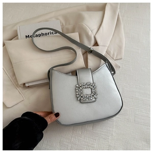 Vue détaillée du sac baguette argenté avec boucle carrée en strass et bandoulière réglable