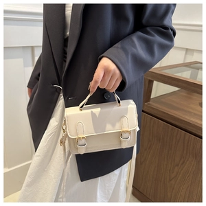 Detail of vintage cream messenger bag featuring golden metallic buckle accents on flap