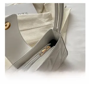 Detalle de bolso de cuero acolchado blanco con cremallera metálica y cierre magnético