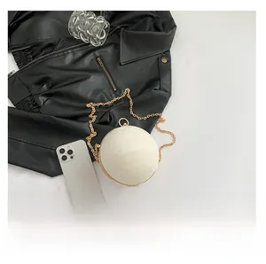 Detailed close-up of a pearly white spherical evening bag with golden chain and hardware