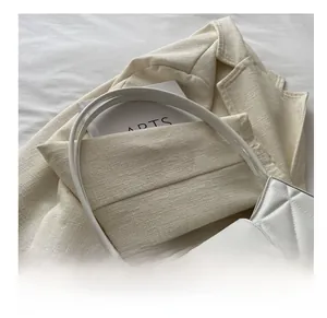 Detalle de bolso acolchado blanco con cierre metálico dorado y correas finas elegantes