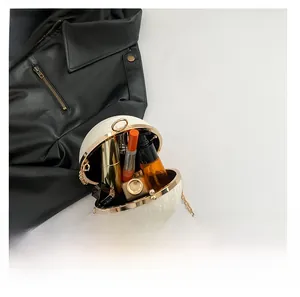 Detail view showing interior capacity of a spherical pearlescent clutch bag with cosmetics
