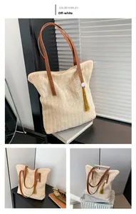 Detail of beige straw tote bag with brown leather straps and yellow tassel accessory