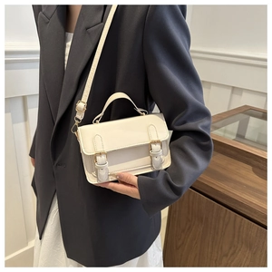 Detail of retro ivory white handbag with golden buckles and adjustable shoulder strap