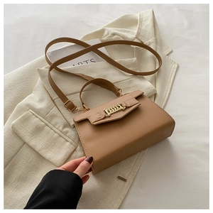 Detail of tan faux leather handbag with gold chain buckle on a beige blazer