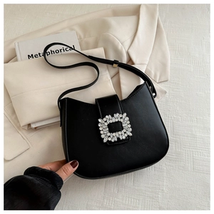 Close-up of elegant black leather baguette bag with a large sparkling crystal buckle