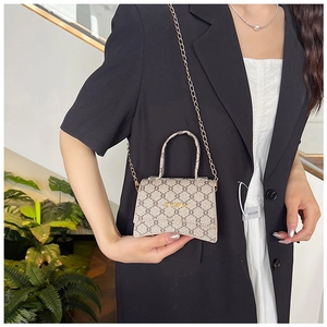 Detail shot of the vintage monogram pattern and gold metal logo on a mini crossbody bag