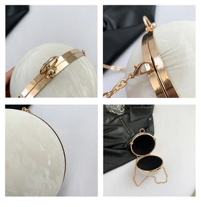 Close-up of marble texture resin spherical clutch bag with golden ring handle and chain