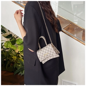 Detail of a structured small hourglass crossbody bag with gold chain strap and top handle
