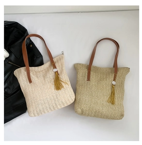 Detail view of woven straw tote bags in beige and brown with chic yellow tassels