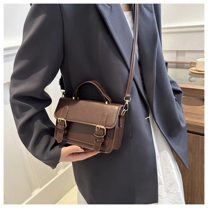Brown vintage messenger bag with double buckles worn by a model in a navy suit
