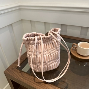 Chic pink pleated drawstring bucket bag with quilted texture and slim shoulder strap