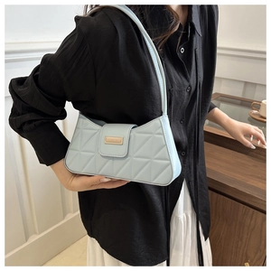 Detail of light blue quilted leather baguette bag with a rectangular gold metal buckle