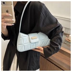 Close-up of light blue PU leather baguette bag with geometric triangular stitching and gold buckle