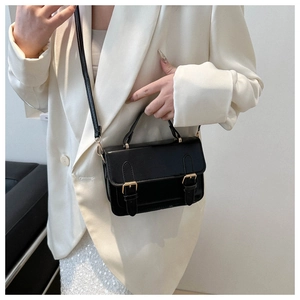 Detail of a vintage black messenger bag with glossy finish and gold metal hardware