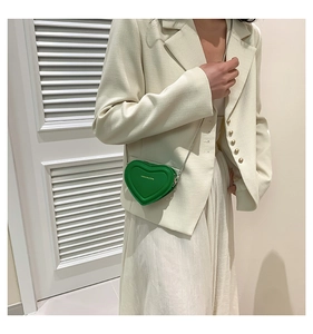Close-up of heart-shaped crossbody bag in vibrant green with elegant gold chain strap