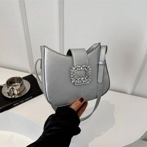 Sac baguette argenté avec boucle en cristal présenté dans une pose élégante à la main