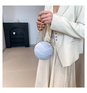 Detail of white marble texture spherical evening bag with elegant gold chain and metal frame
