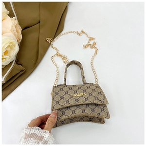 Detail of vintage patterned hourglass crossbody bag with gold chain and metal plaque