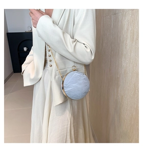 Close-up of a blue spherical evening bag with crinkle texture and gold chain strap