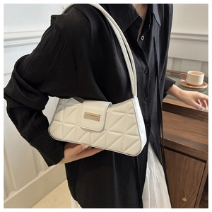Detail of white quilted texture and gold metal buckle on a French style baguette bag