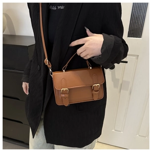 Detail of a brown leather vintage crossbody bag with gold buckles and top handle