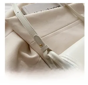 Detail view of the adjustable white leather shoulder strap with gold metal buckle hardware