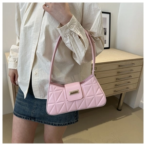 Detail of pink quilted shoulder bag with gold clasp shown on model in a cozy interior