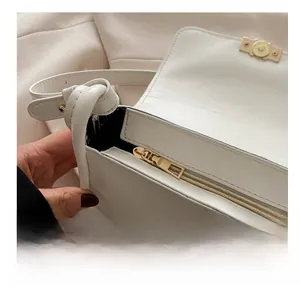 Detail view of smooth golden zipper hardware on white leather crossbody bag