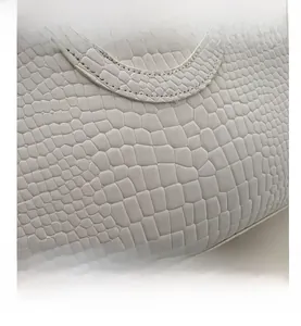 Close-up of white embossed crocodile leather texture and fine stitching on the shoulder bag