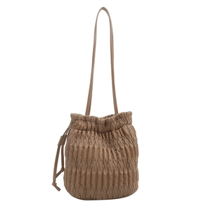 Minimalist tan quilted bucket bag with drawstring closure and thin shoulder strap