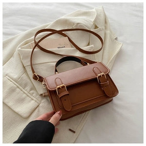 Detail of vintage brown leather handbag with double buckle flap and matte finish texture