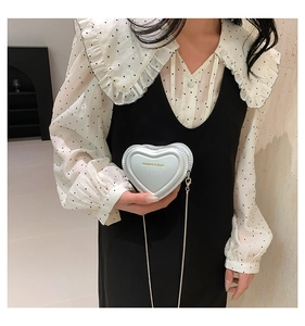 Detail of light blue heart-shaped mini bag with gold fashion lettering and chain strap