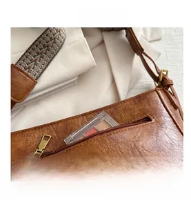 Détail du sac seau marron rétro avec bandoulière tissée et finitions métalliques vintage