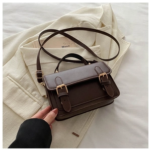Macro view of retro dark brown messenger bag with vintage metal buckles and leather texture