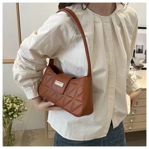 Detalle de bolso de hombro acolchado marrón vintage con cierre dorado y costuras retro