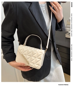 Detailed view of white quilted PU leather crossbody bag with metallic accent on a model
