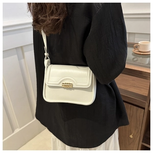 Detail of a minimalist beige leather shoulder bag with a rectangular gold metal twist lock