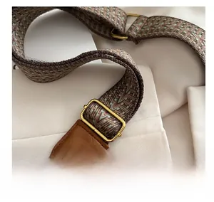 Détail de la bandoulière tissée bohème avec boucle dorée et finitions en cuir