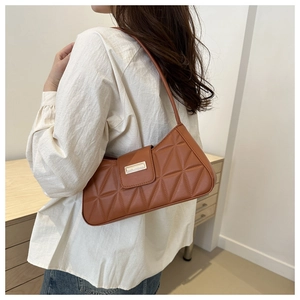 Close-up of caramel baguette bag with triangle geometric quilting and silver metal clasp