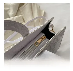 Detail of white crocodile embossed handbag with premium gold metal zipper and PU leather texture