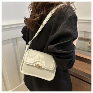 Detail of white PU leather shoulder bag with gold cylindrical buckle and fine stitching